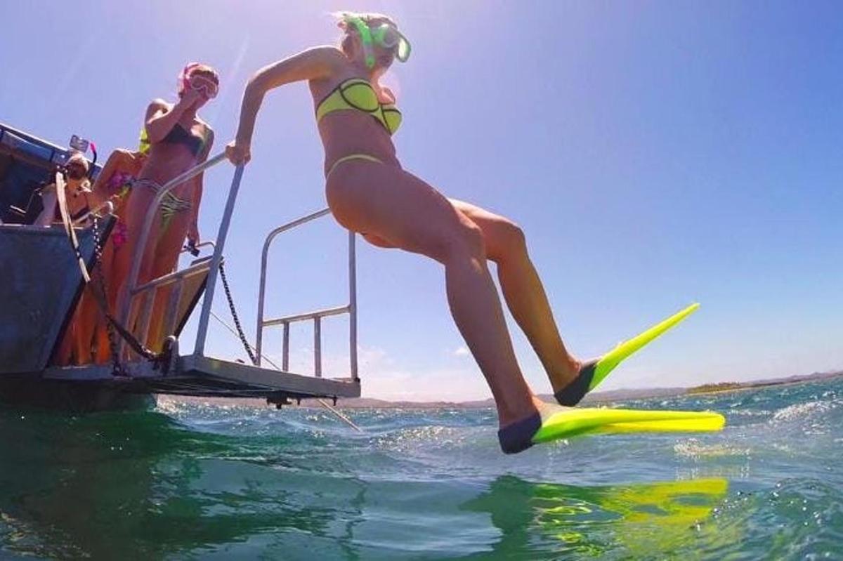 a woman jumping into the water on a boat