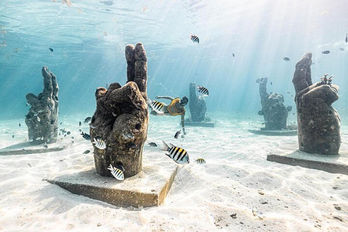 a statue in the ocean with fish in the water