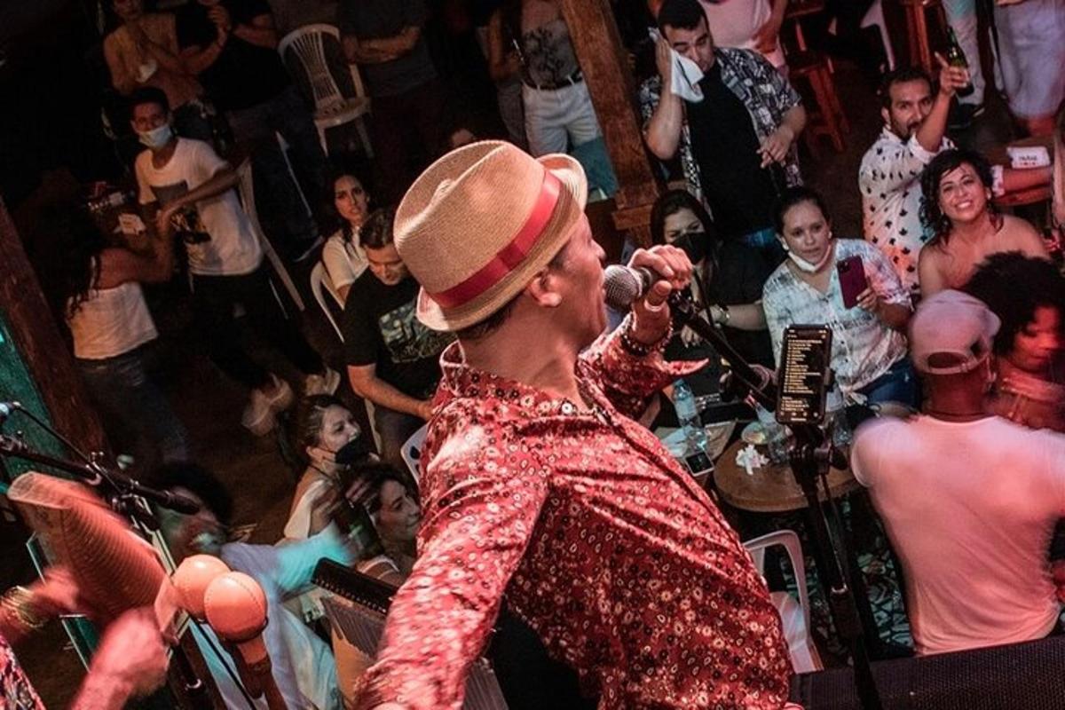 Un hombre cantando en un micrófono entre una multitud de personas.