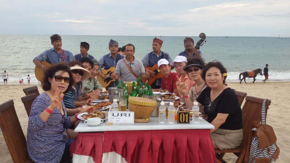 a group of people sitting at a table on the beach