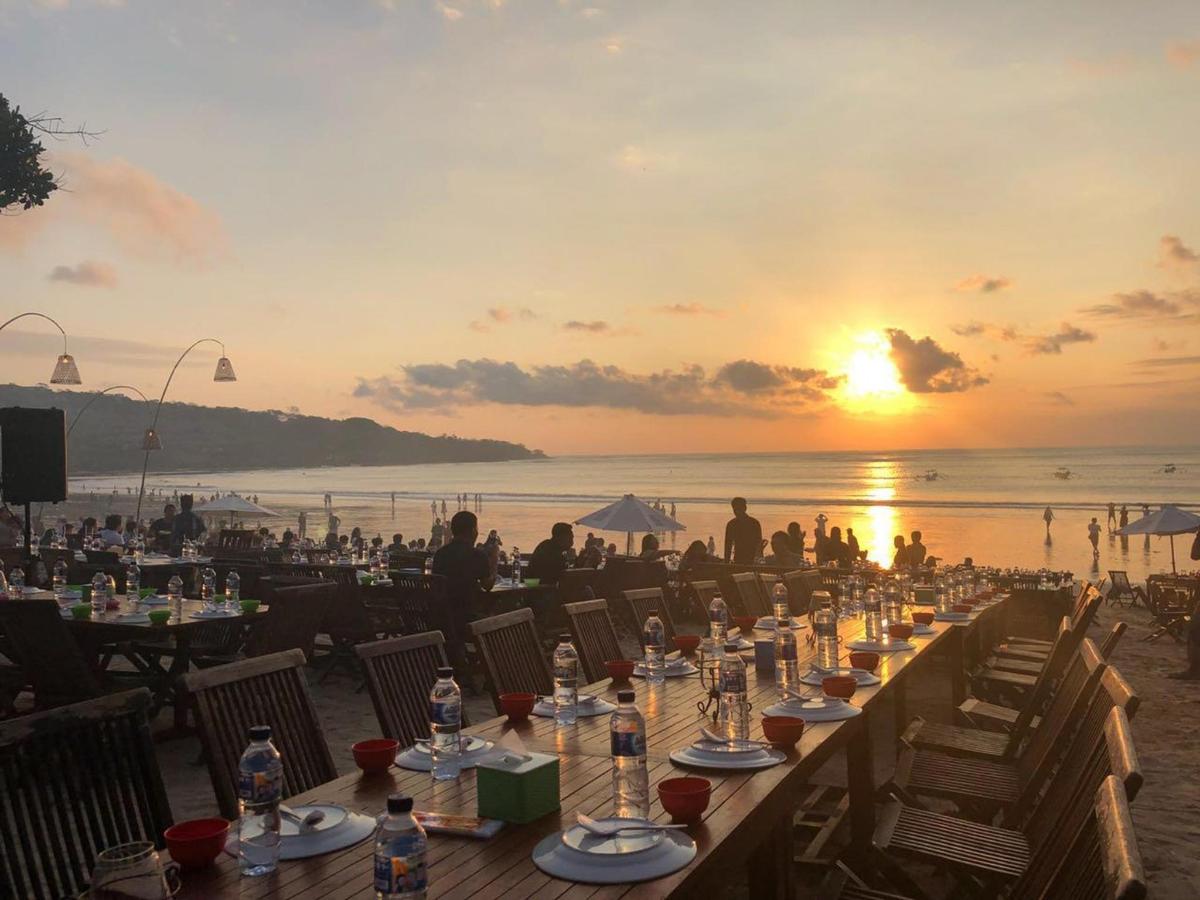 a long table on the beach with the sunset in the background