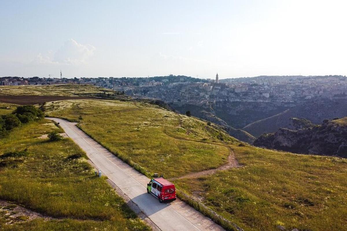 a red van driving down a road on a hill