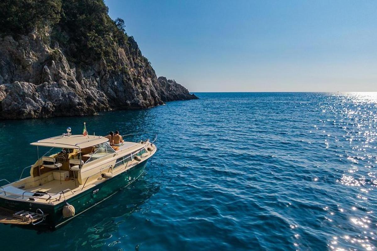 a boat floating in the water next to a cliff