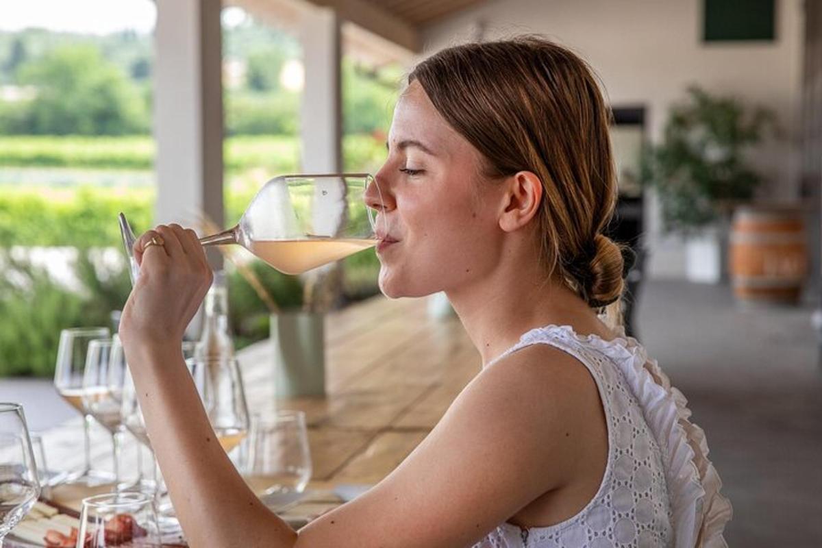 žena sedící u stolu a pije sklenici vína
