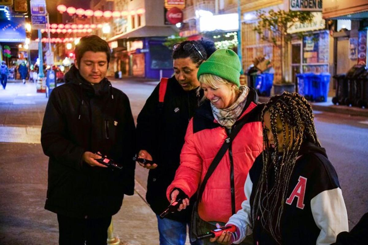a group of people walking down a street looking at their cell phones
