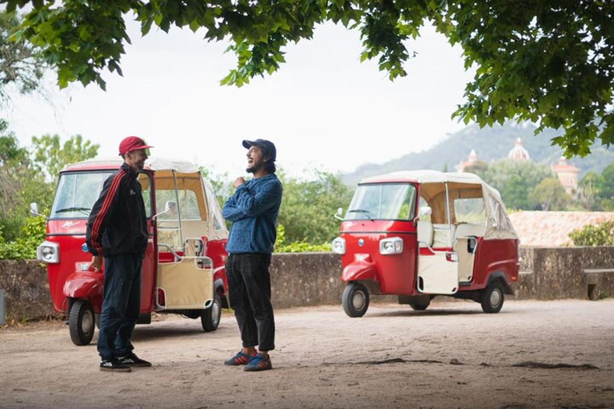 dua pria berdiri di depan dua kendaraan kecil