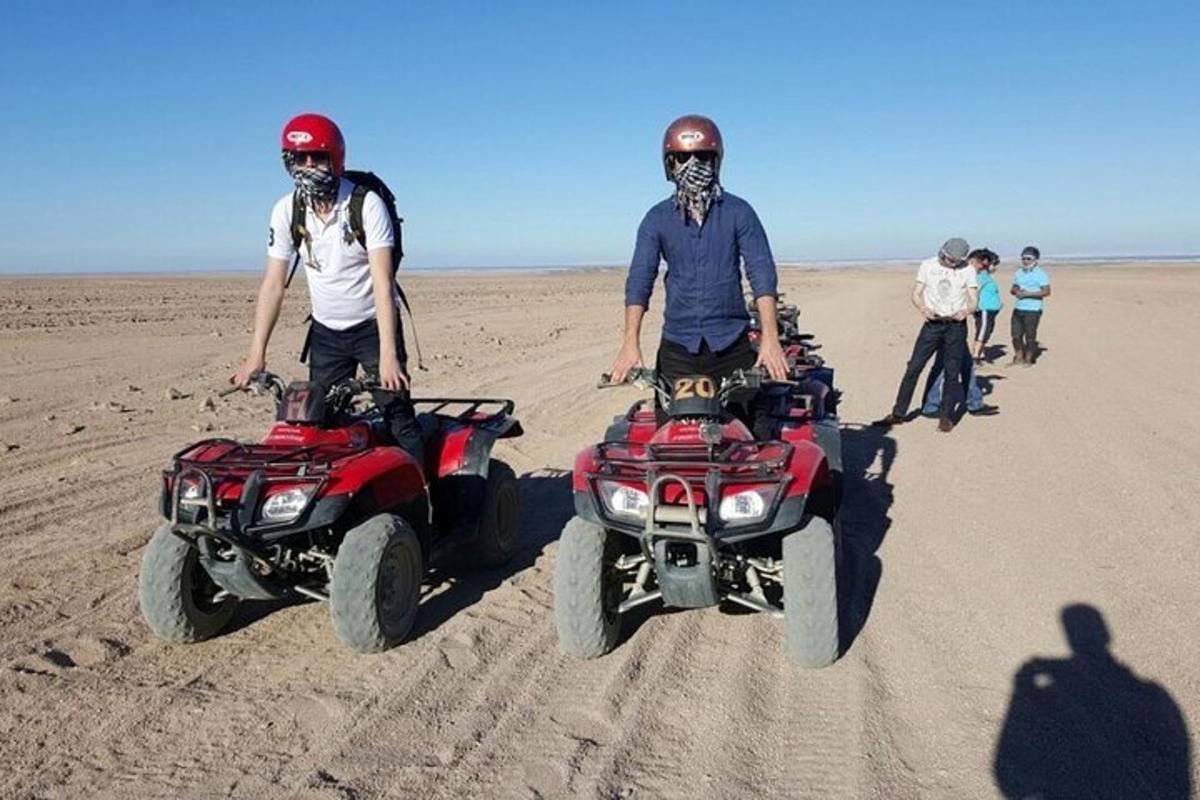 Dos hombres están parados en vehículos todo terreno en el desierto.