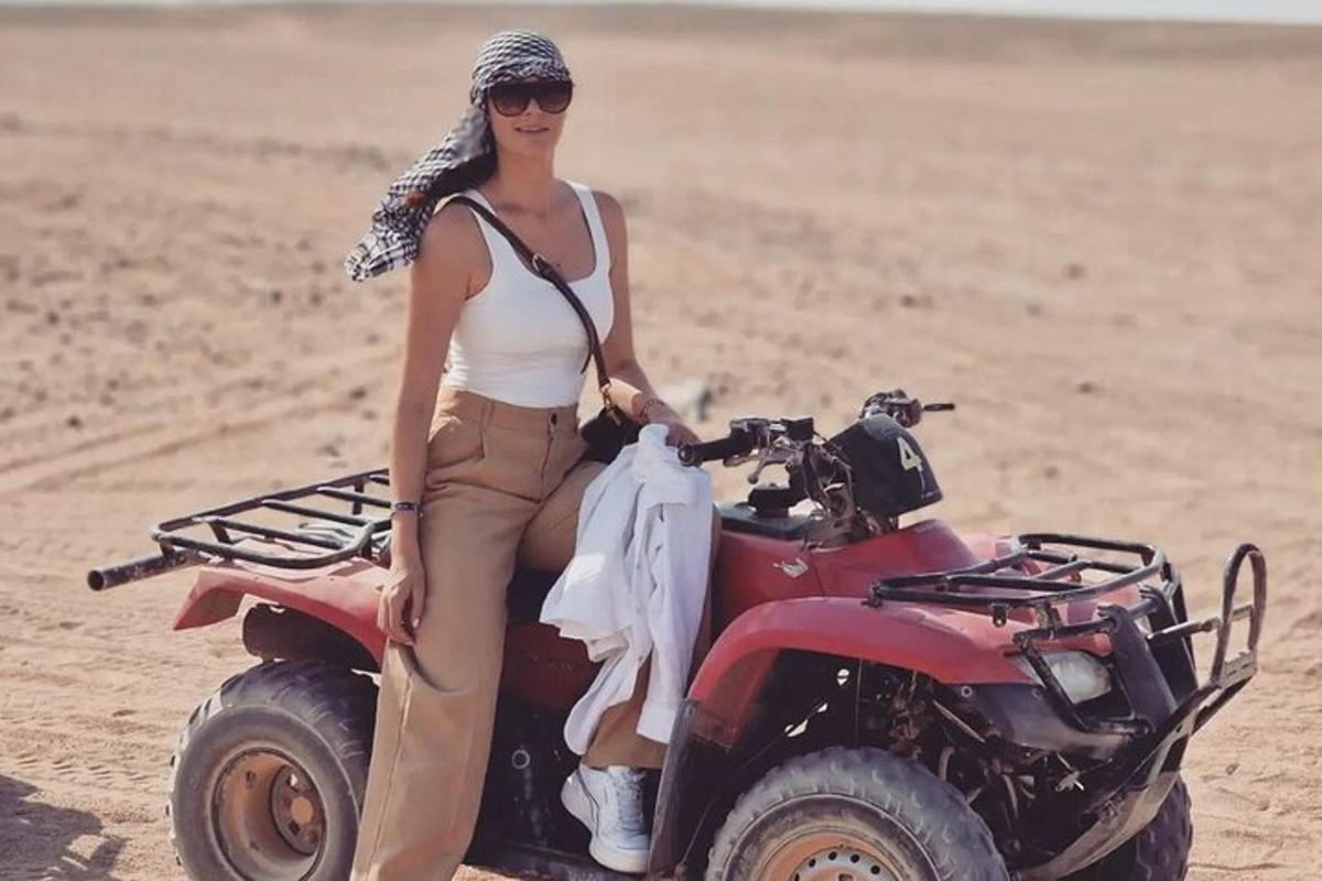 una donna seduta su un quad nella sabbia