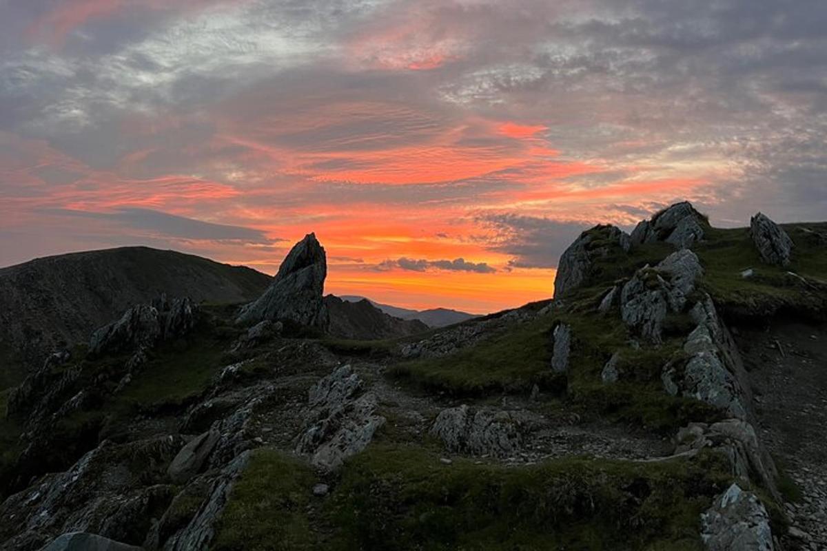 a sunset on a mountain with rocks in the foreground