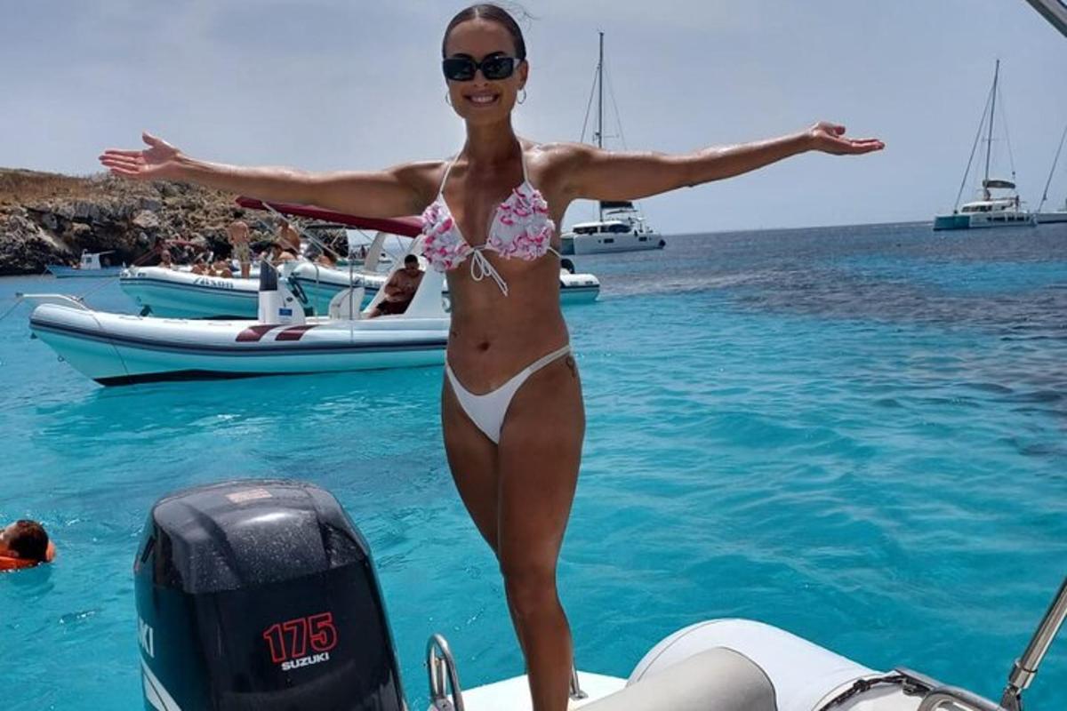 a woman in a bikini standing on a boat in the water