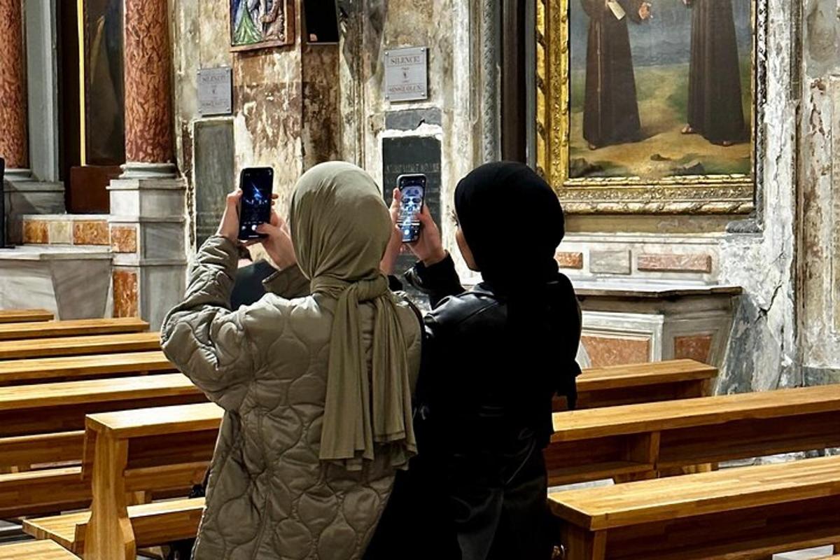 Két nő mobiltelefonnal fényképez egy templomot