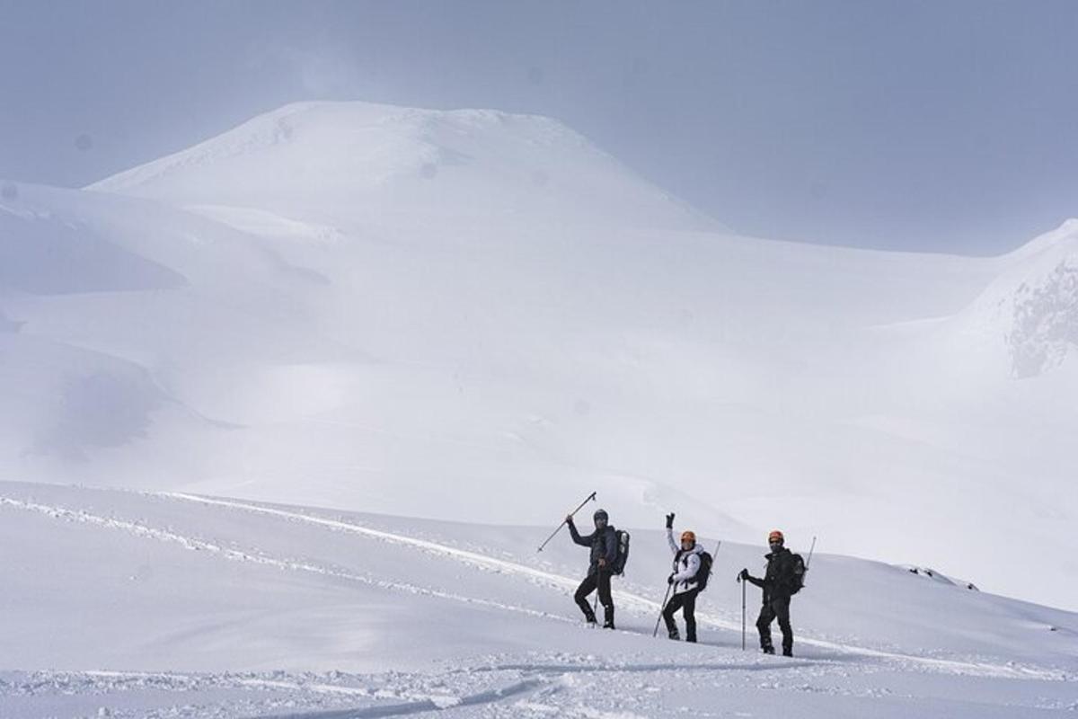 a group of three people walking up a snow covered slope