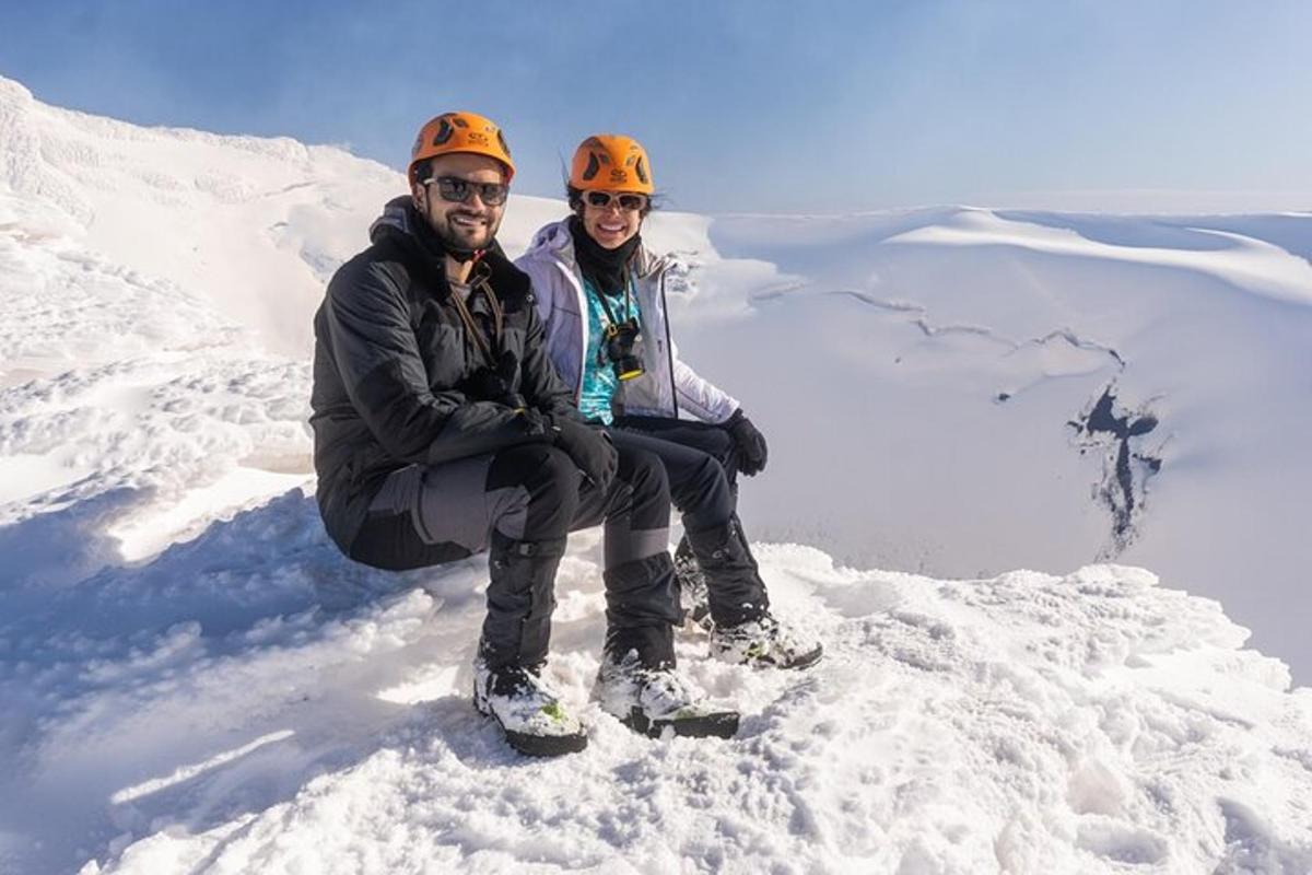 a man and woman sitting on top of a snow covered mountain