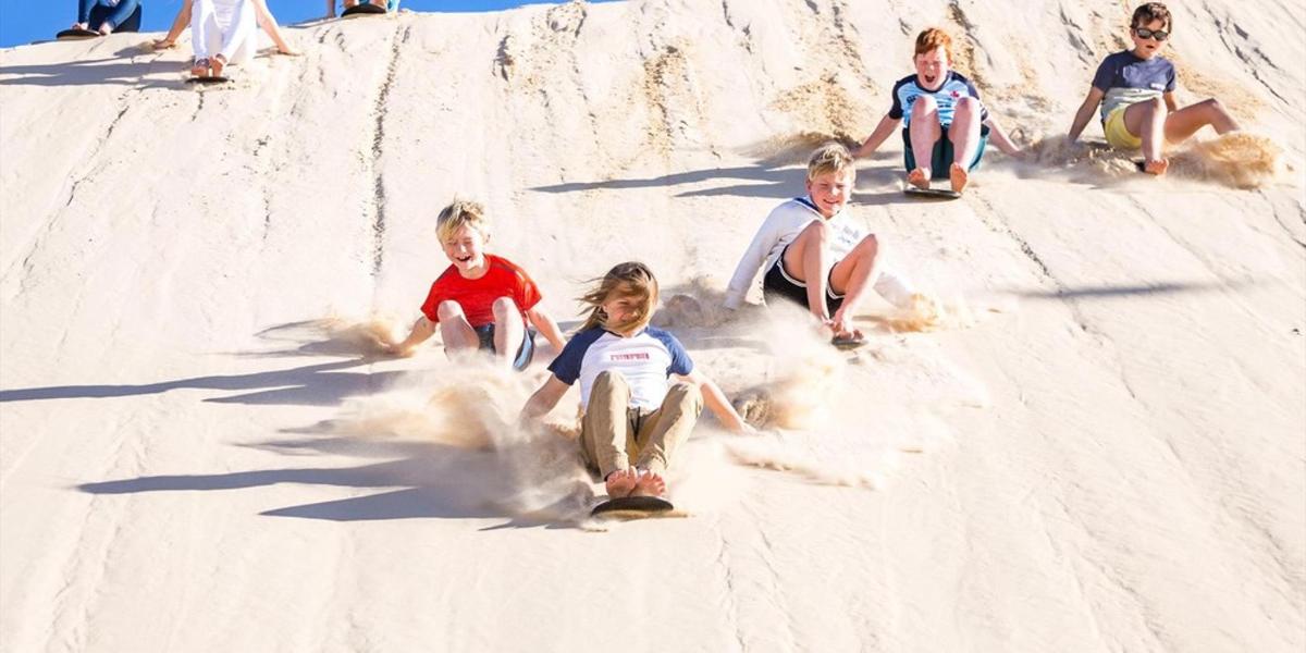 eine Gruppe von Kindern, die im Sand sitzen