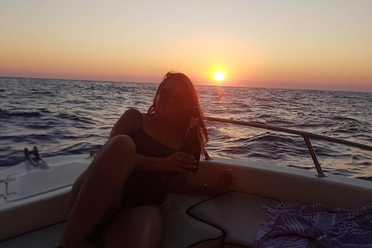 žena sediaca na lodi v oceáne pri západe slnka