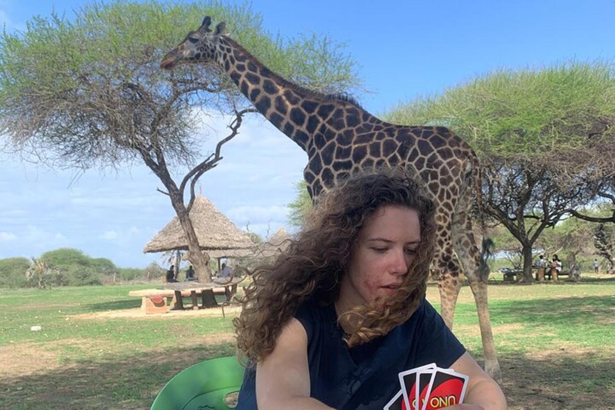 una dona asseguda davant d'una girafa