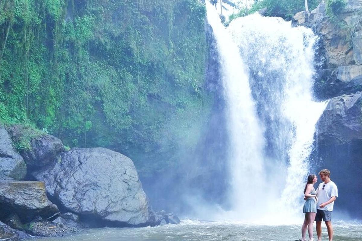 dues persones dempeus a l'aigua davant d'una cascada