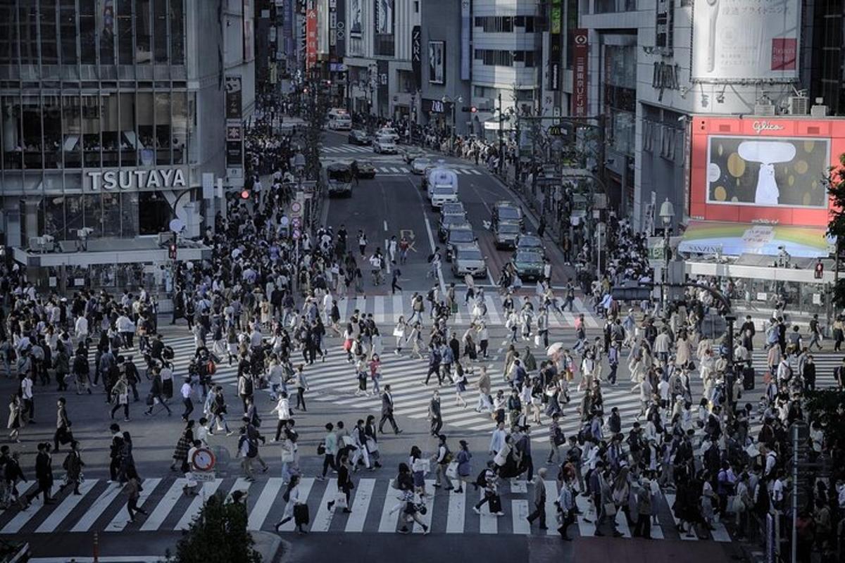uma multidão de pessoas atravessando uma rua em uma cidade movimentada