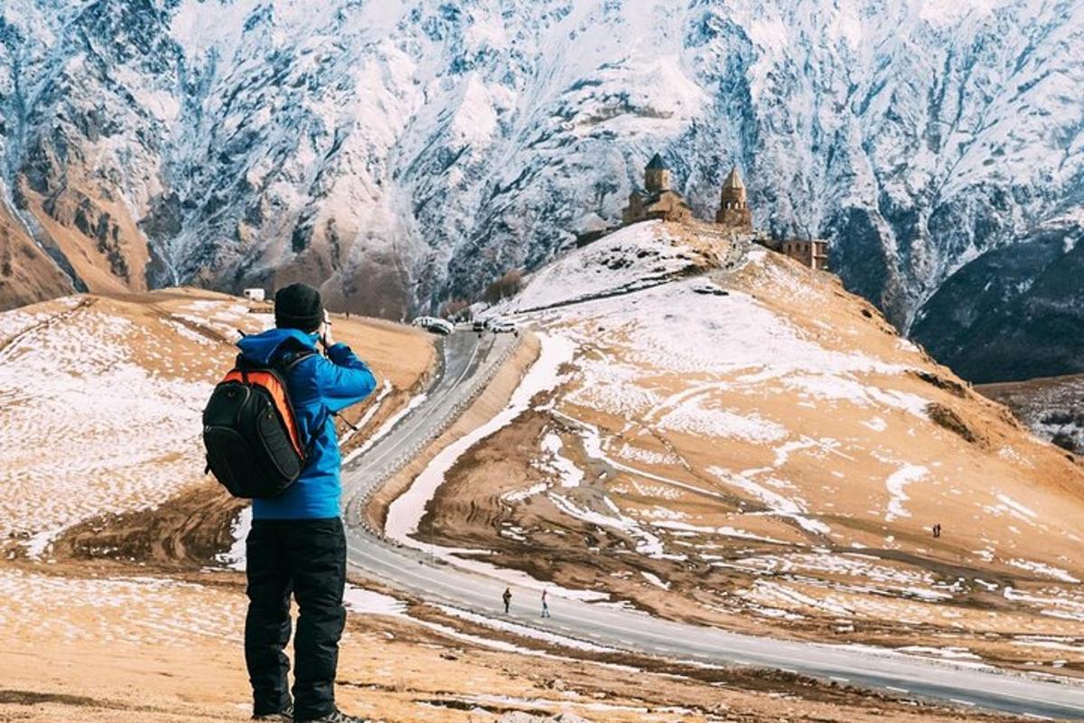 a man with a backpack taking a picture of a mountain