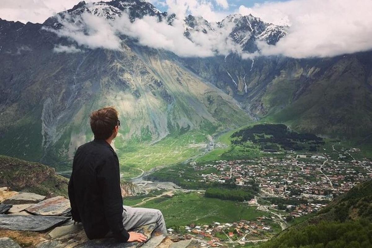 a man sitting on top of a mountain looking at a valley