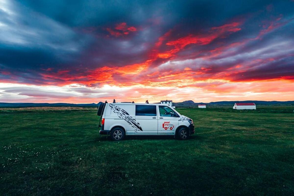 une camionnette blanche garée dans un champ avec un coucher de soleil