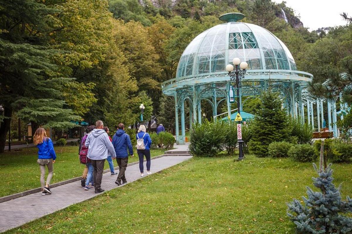 a group of people walking in a park with a gazebo