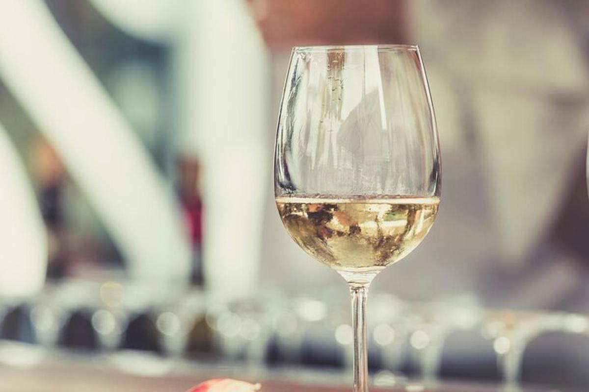 a glass of white wine sitting on a table