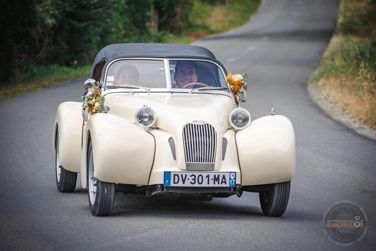 an old white car driving down a road