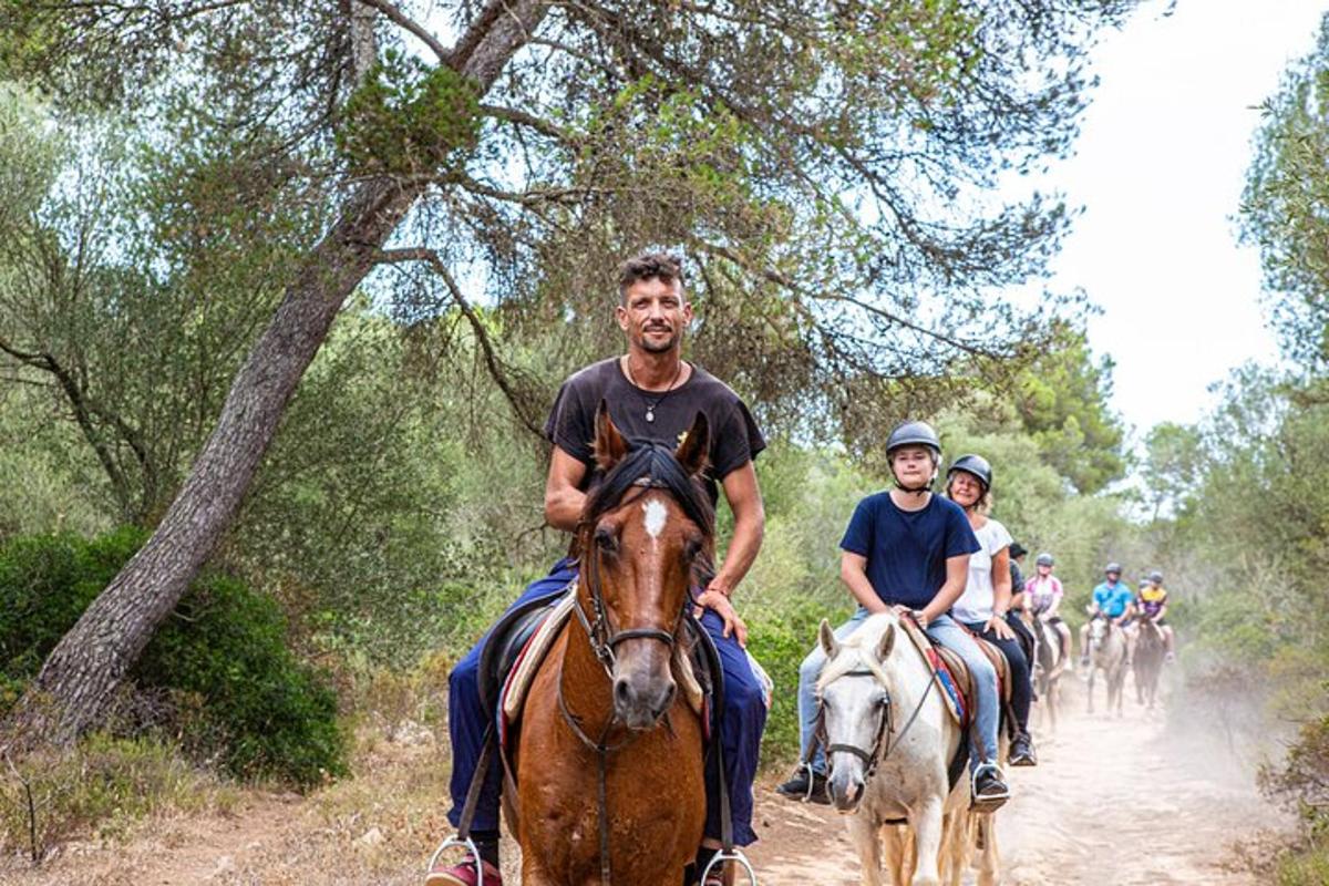 Un grupo de personas montando a caballo por un camino de tierra.