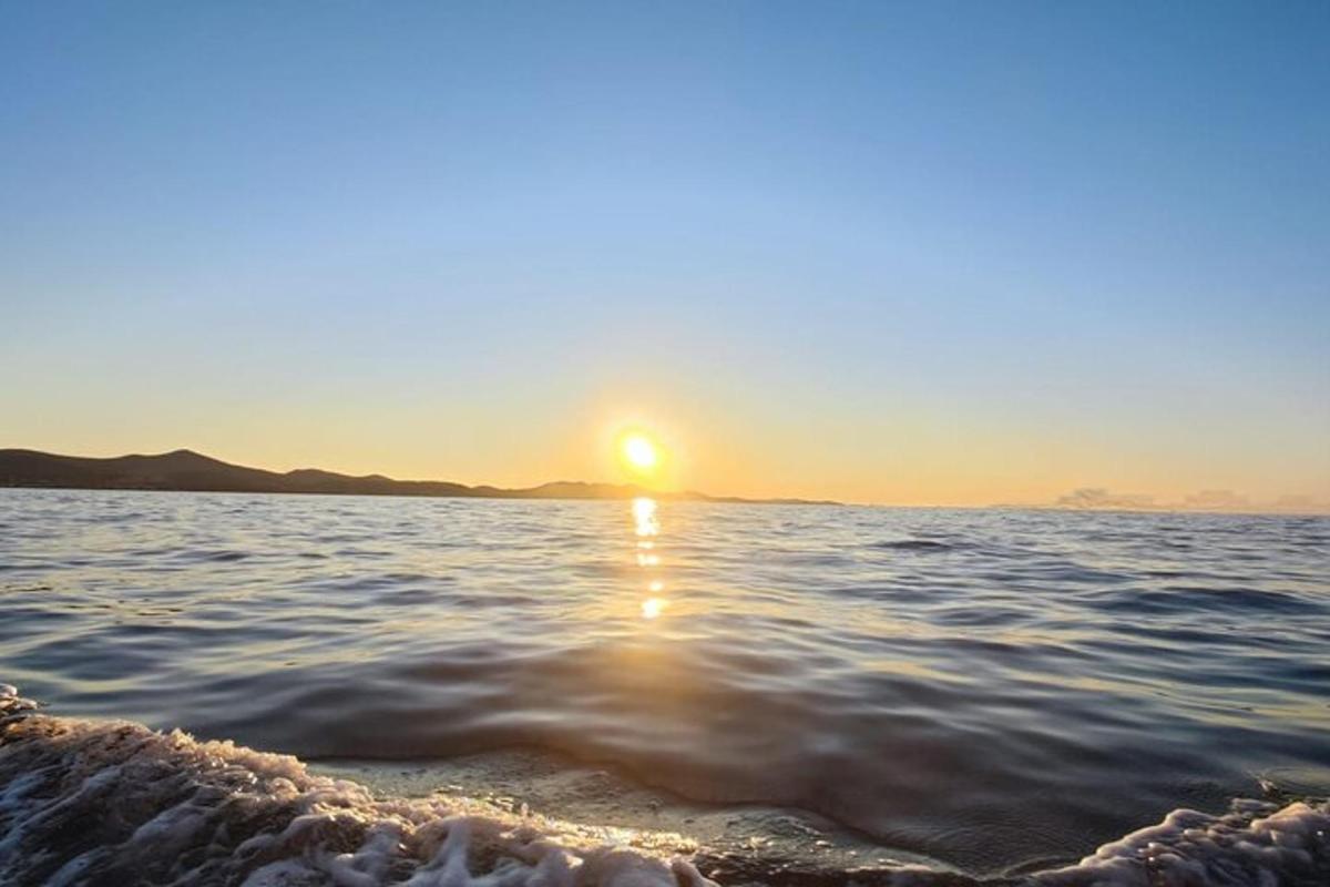 ένα ηλιοβασίλεμα πάνω από το νερό με τη δύση του ηλίου