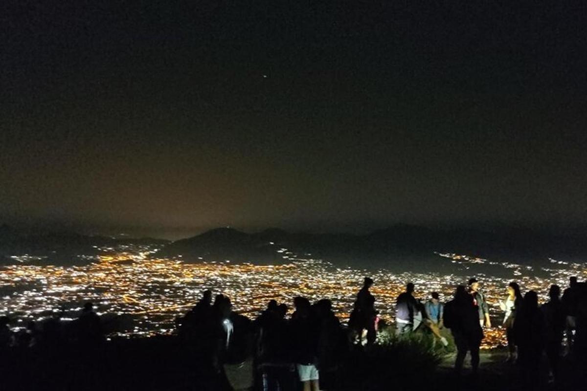 Un grupo de personas de pie en una colina por la noche.