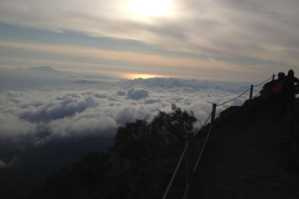Un grupo de personas de pie en la cima de una montaña sobre las nubes.