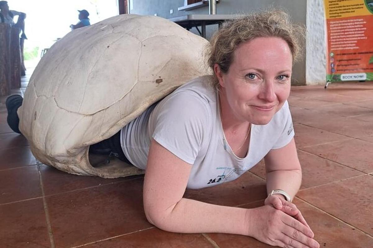 a woman laying on the floor next to a giant tortoise