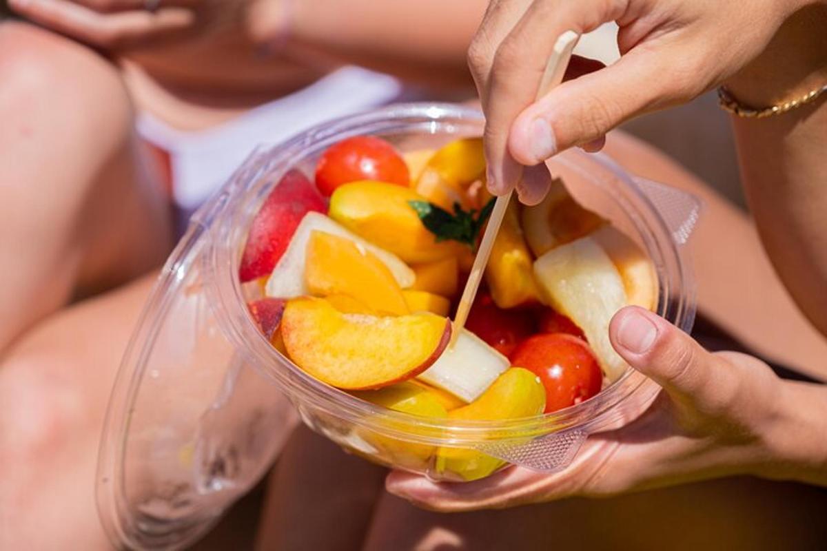inimene, kes hoiab käes läbipaistvat kaussi puuviljadega