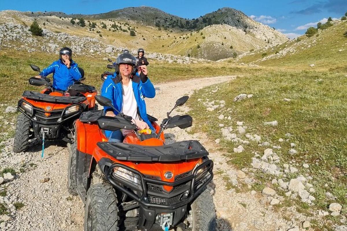 two people riding on atvs on a dirt road