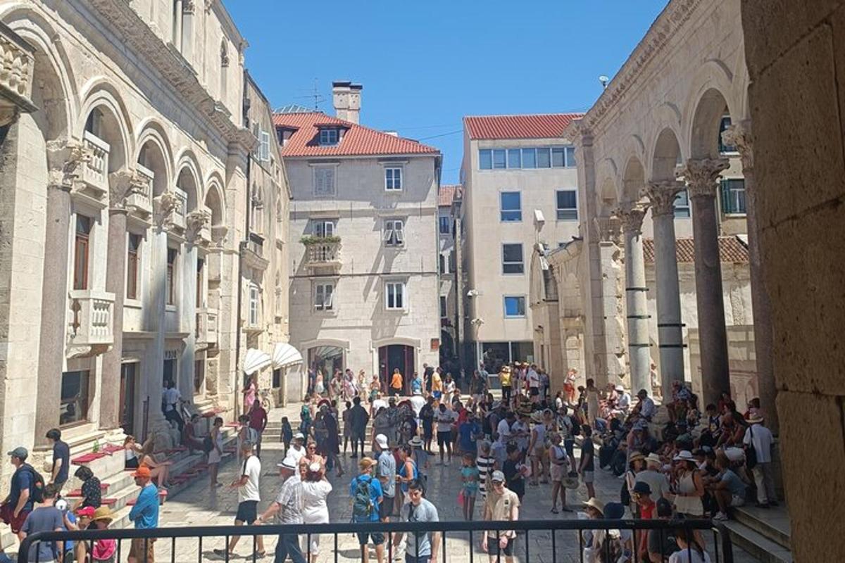 a crowd of people walking down a street between buildings