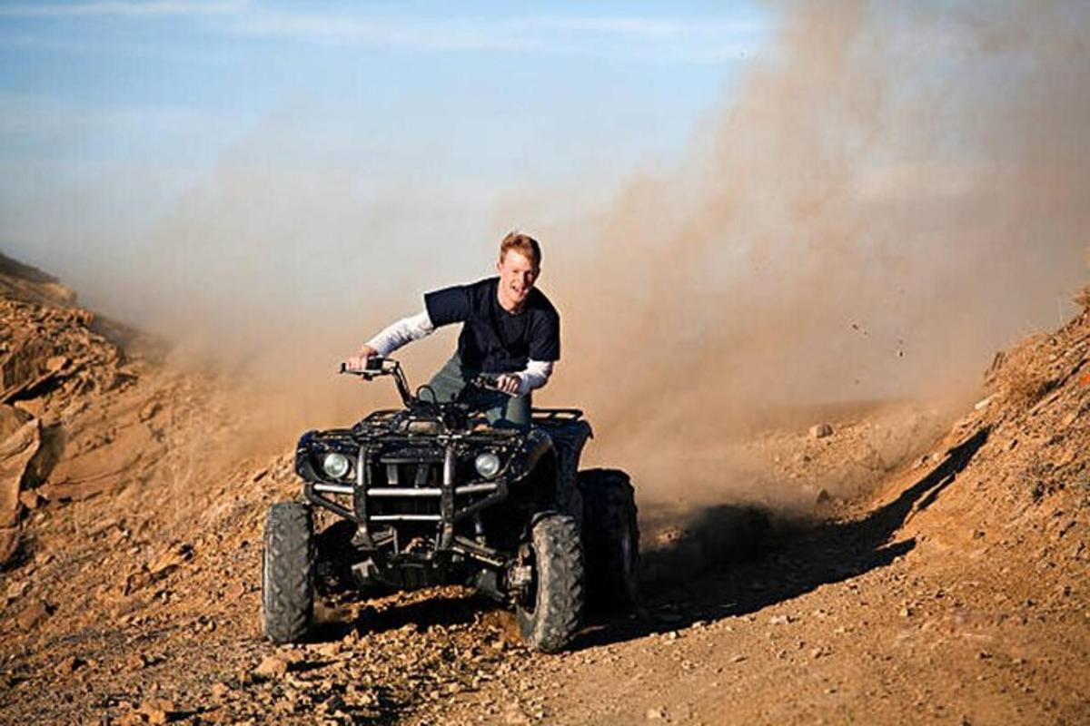a man riding a four wheeler on a dirt road