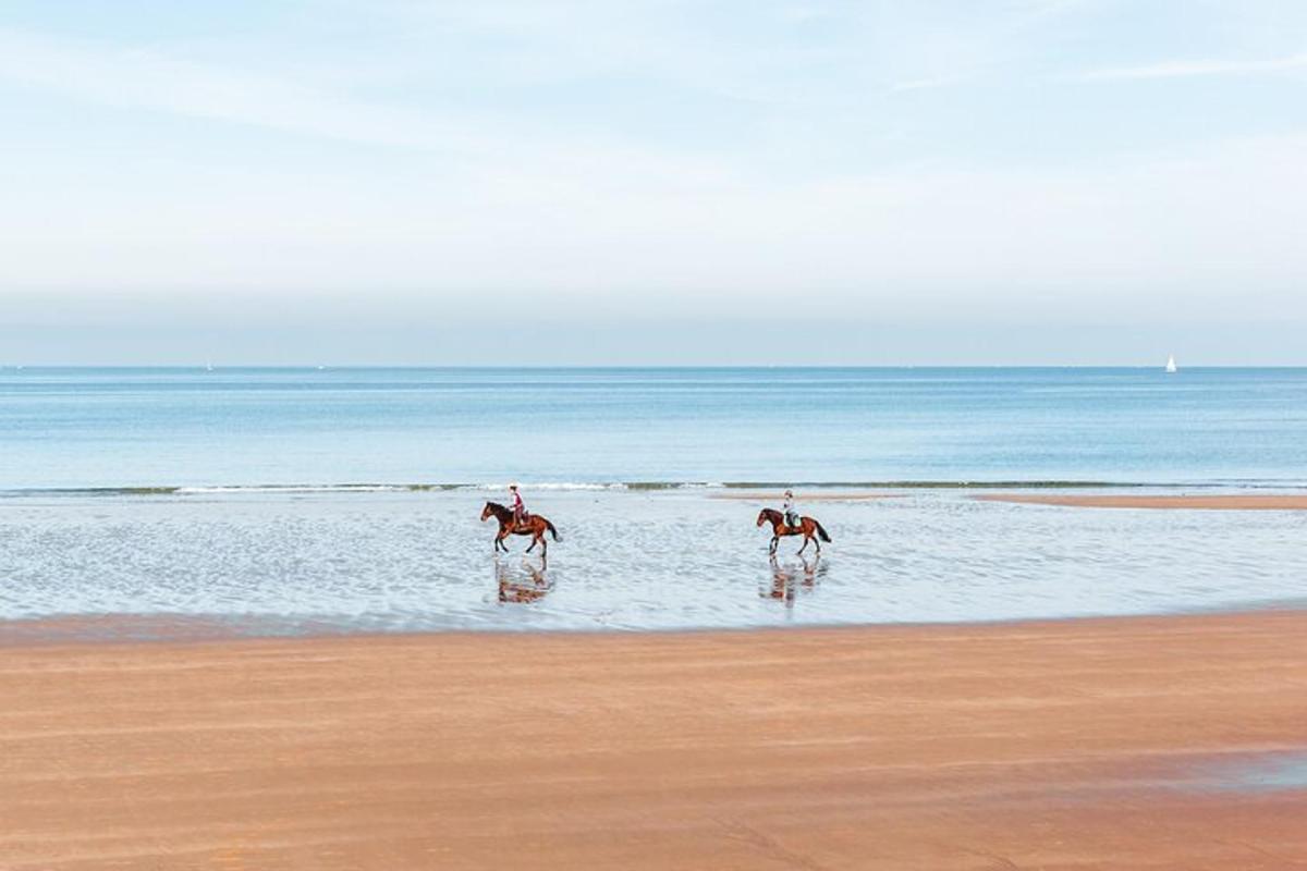 due persone a cavallo nell'acqua sulla spiaggia