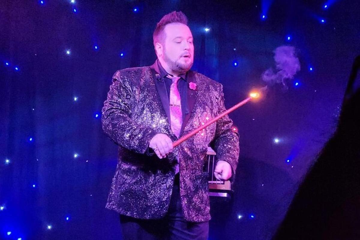 a man in a suit holding a wand on a stage