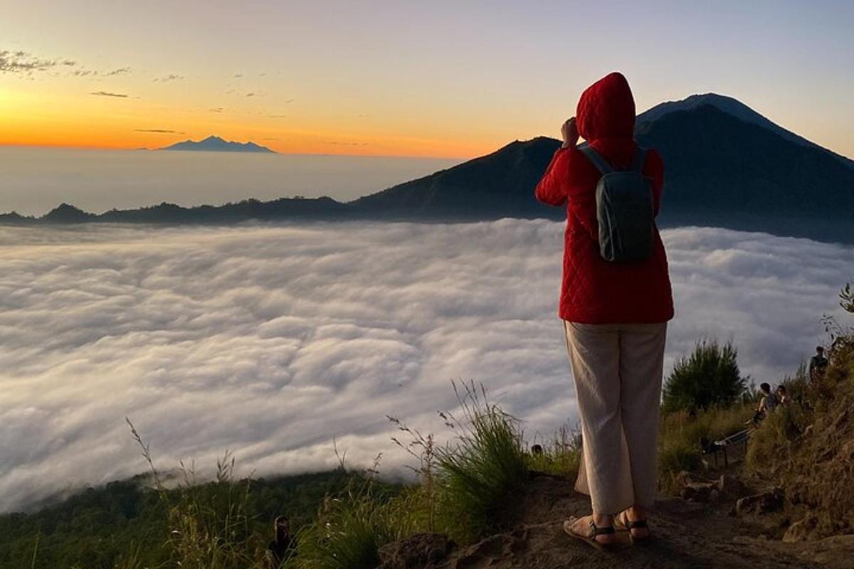 seorang wanita berdiri di atas gunung melihat awan
