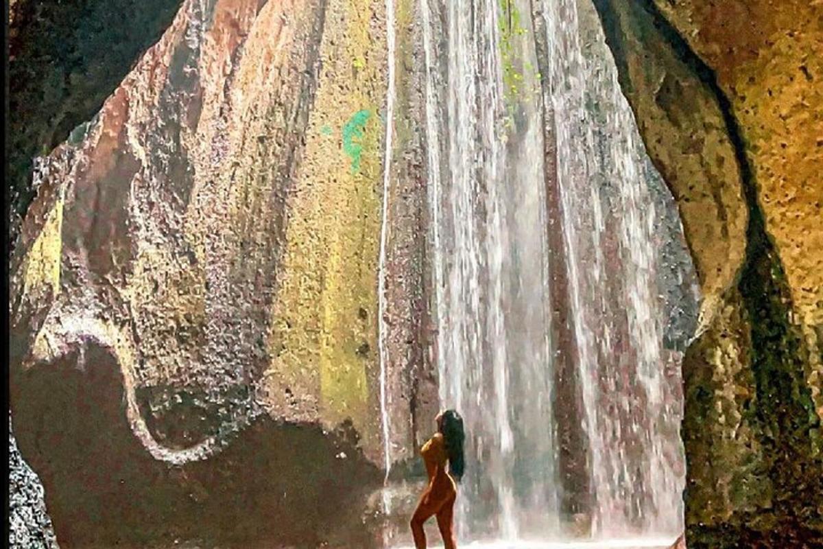seorang wanita berdiri di hadapan air terjun