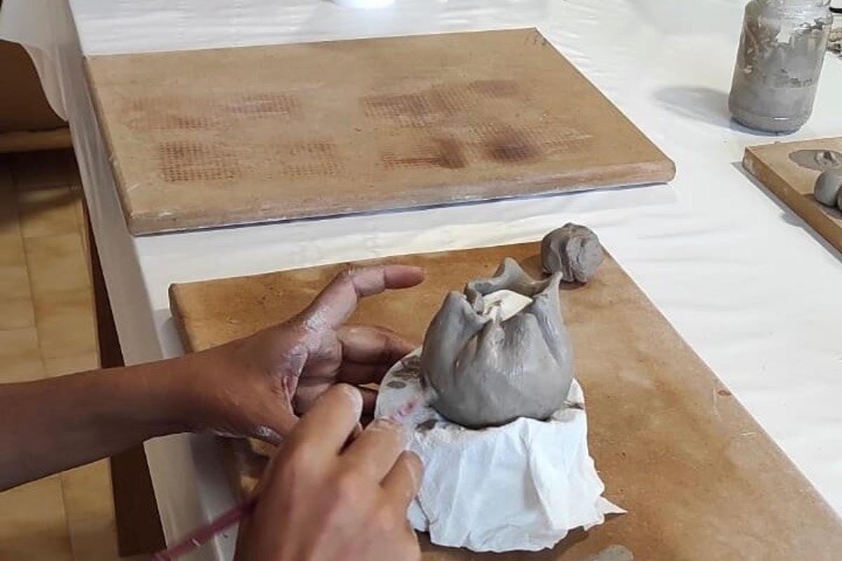 Una persona está haciendo una olla de barro sobre una mesa.
