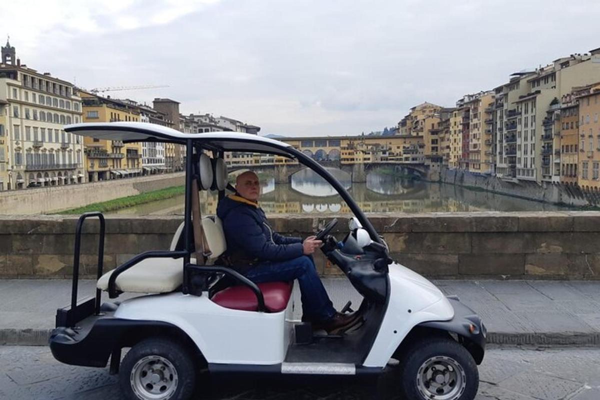 um homem sentado em um carrinho de golfe na rua