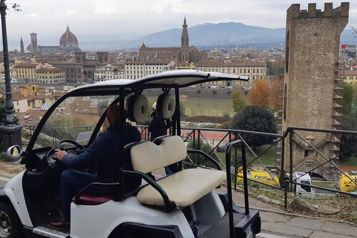 um casal sentado em um carrinho de golfe com vista para uma cidade