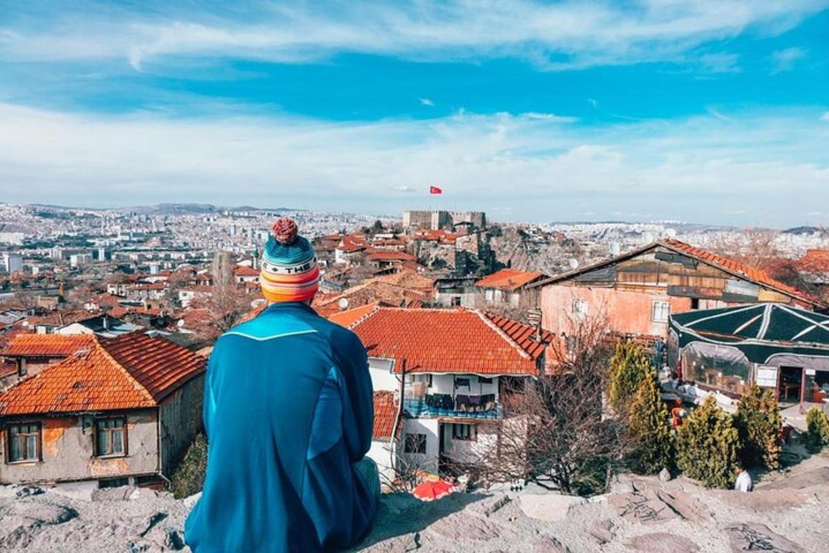 a man sitting on a hill looking at a city