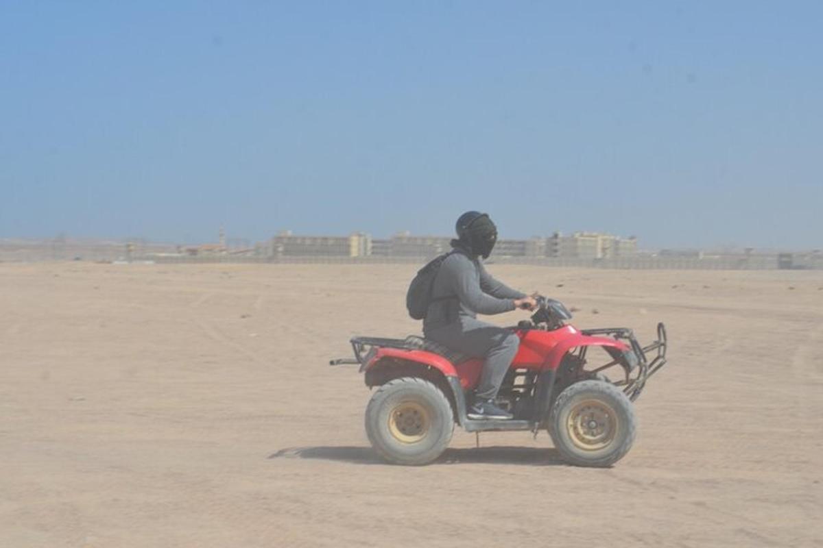 un uomo che guida un quad rosso nel deserto