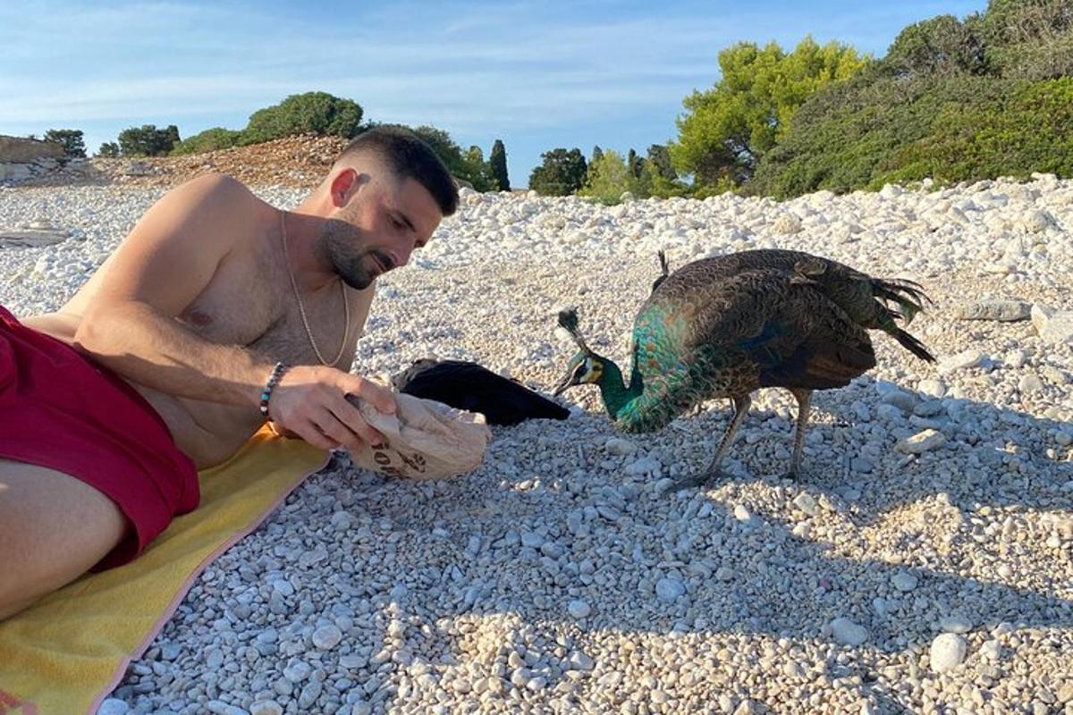 ein Mann, der mit einem Vogel am Strand sitzt