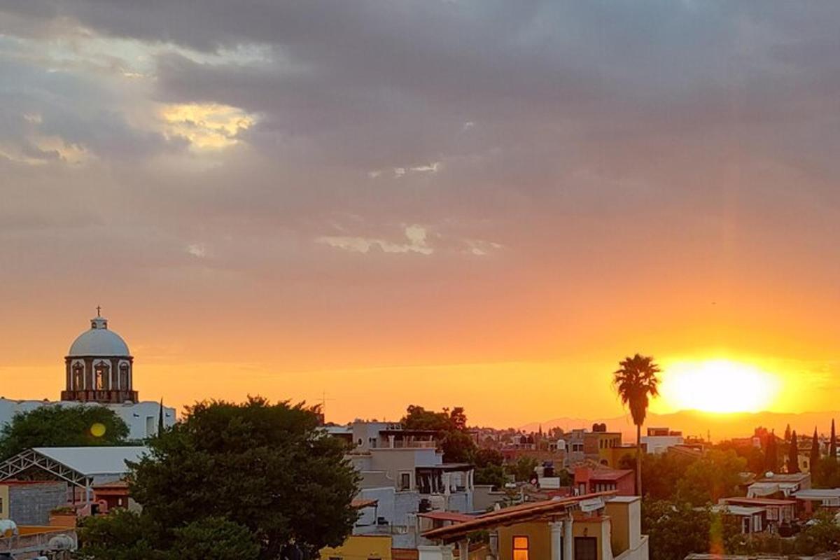 Una puesta de sol sobre una ciudad con una torre de reloj