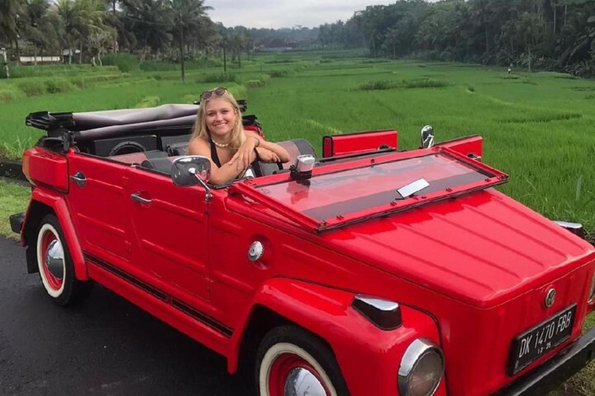 a woman is sitting in a red convertible car