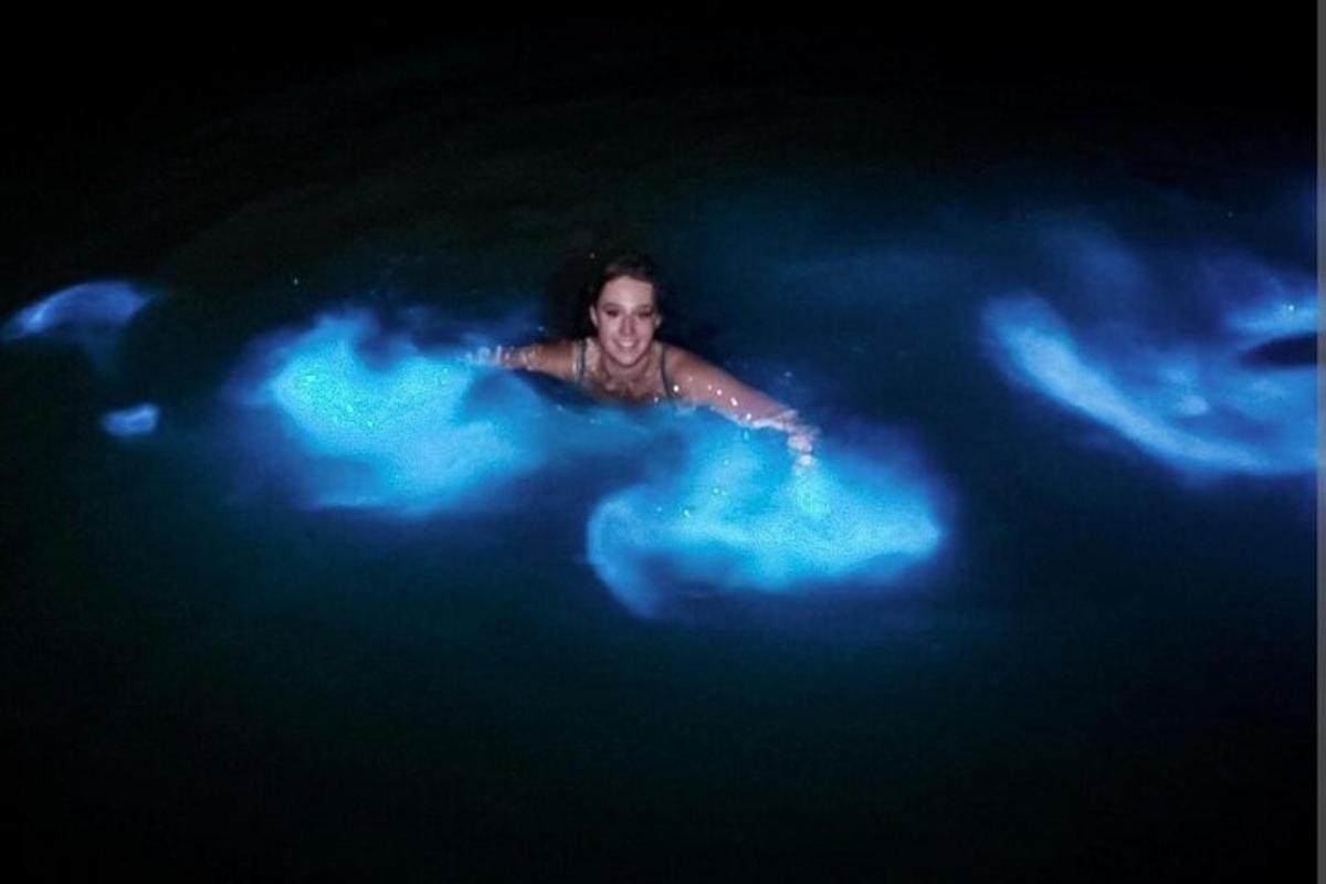 a man swimming in a pool with blue lights